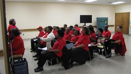 All dressed in matching red shirts, the Songbirds choir rehearse a song.