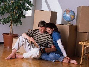 Man and woman looking at photo album with stack of boxes behind them