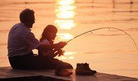 A father and daughter fishing during a sunset